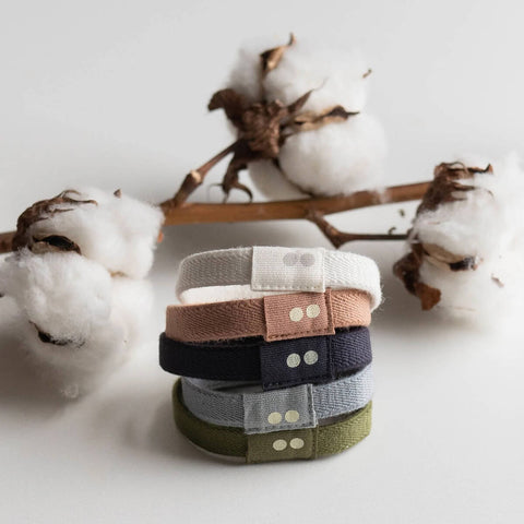 Stack of fabric bands with a branch of cotton flowers in the background