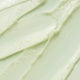 Texture of KORA Organics Active Algae Calming Cleansing Balm, showing it's lime green colour. A cleanser with microalgae, pineapple enzymes, jojoba and squalane that cleanses away makeup, dirt and oil for a clearer, more balanced complexion.