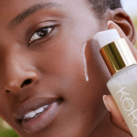 Model pumping a small amount of cleansing oil onto her cheek. 