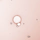 Swatch of serum - liquid texture, pinkish tint with a few bubbles.