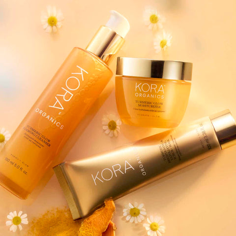 Kora Organics Turmeric skincare products on a soft yellow background with flowers.