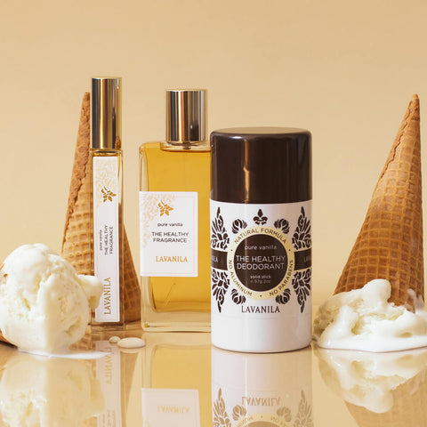 Lavanila The Healthy Deodorant Pure Vanilla lifestyle shot of the stick beside perfume bottles and ice cream cones on a cream backdrop