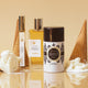 Lavanila The Healthy Deodorant Pure Vanilla lifestyle shot of the stick beside perfume bottles and ice cream cones on a cream backdrop