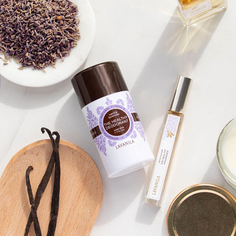 Lavanila The Healthy Deodorant Vanilla Lavender 57g overhead lifestyle shot of the stick beside a roller, vanilla pods and a bowl of lavender