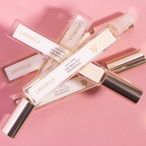 Lavanila The Healthy Fragrance Pure Vanilla 10ml lifestyle shot of several roller bottles lying across a pink backdrop, styled lifestyle photo