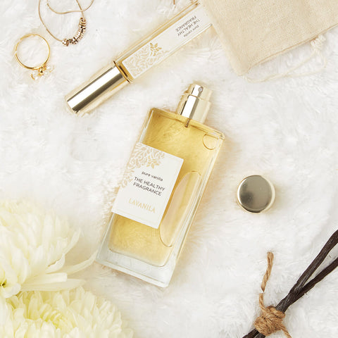 Lavanila The Healthy Fragrance Pure Vanilla 50ml lifestyle flat lay of the bottle and a roller with vanilla pods and white flowers