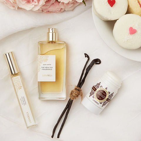 Lavanila The Healthy Fragrance Pure Vanilla 50ml lifestyle flat lay of the bottle, a roller and a deodorant stick with vanilla pods and iced cupcakes