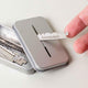 Leaf Shave Single-Edge Blades 50 blades lifestyle shot of a hand sliding a blade into the open metal recycling tin, styled lifestyle photo
