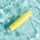 Yellow bullet massager partially submerged in clear blue water.