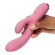 Pink dual vibrating massager held by a hand on a white background.