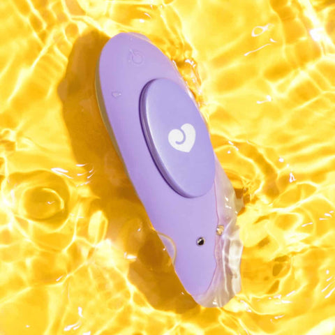 Waterproof purple silicone vibrator in water on a yellow background. 
