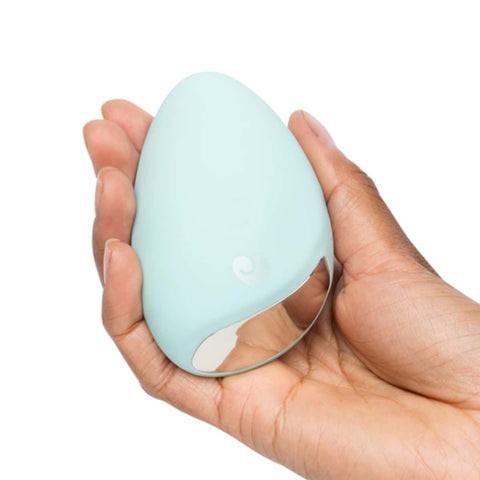 Light blue egg-shaped personal massager held in a hand against a white background.