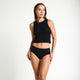 Model wearing Modibodi Basic Mid-Rise Brief Light-Moderate in black, front view of period underwear.