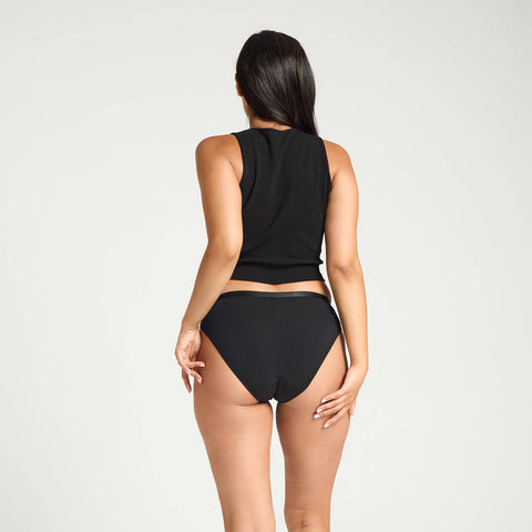 Model wearing Modibodi Classic Bikini Light-Moderate in black, back view of period underwear.