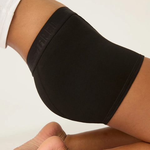 Model wearing Modibodi Teen Hipster Boyshort Moderate-Heavy in black, side view of period underwear.
