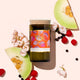 Mojo Candle Co. Australiana Reclaimed Wine Bottle Soy Wax Candle Kakadu Plum lifestyle shot with melon slices, peppercorns and flowers on peach