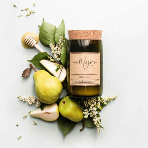 Mojo Candle Co. Reclaimed Wine Bottle Soy Wax Candle French Pear lifestyle shot of the corked bottle candle among fresh pears and white flowers