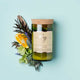 Mojo Candle Co. Wine Bottle Soy Wax Candle Oakmoss & Sage lifestyle shot of the bottle candle among citrus slices and leaves on an aqua backdrop