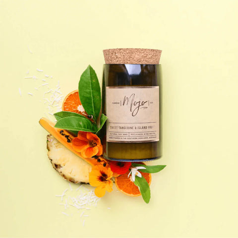 Mojo Candle Co. Reclaimed Wine Bottle Soy Wax Candle Sweet Tangerine & Island Fruits lifestyle shot of the bottle candle with orange slices on yellow