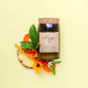 Mojo Candle Co. Reclaimed Wine Bottle Soy Wax Candle Sweet Tangerine & Island Fruits lifestyle shot of the bottle candle with orange slices on yellow