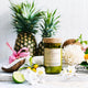 Mojo Candle Co. Reclaimed Wine Bottle Soy Wax Candle Sweet Tangerine & Island Fruits lifestyle shot of the candle among a pineapple and coconut