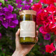 Mojo Candle Co. Wine Bottle Soy Wax Candle Violet & Frosted Berries lifestyle shot of a hand holding the bottle candle among pink bougainvillea