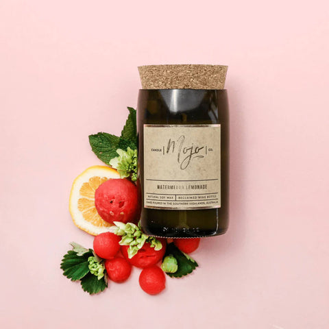 Mojo Candle Co. Wine Bottle Soy Wax Candle Watermelon Lemonade lifestyle shot of the bottle candle beside strawberries and lemon slices on pink