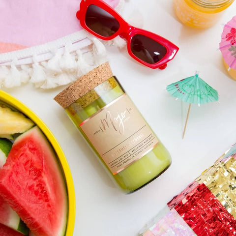 Mojo Candle Co. Wine Bottle Soy Wax Candle Watermelon Lemonade lifestyle shot of the bottle candle beside watermelon, red sunglasses and umbrellas