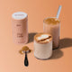 Morning Made Chai Latte Original Blend 300g lifestyle shot of the peach tin beside two iced chai lattes and a scoop of spice powder