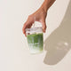 Morning Made Matcha Latte Mango Blend 300g lifestyle shot of a hand holding a clear cup of layered green matcha drink, styled lifestyle photo