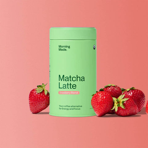 Morning Made Matcha Latte Strawberry Blend lifestyle shot of the green tin among fresh strawberries on a pink red backdrop, styled lifestyle photo