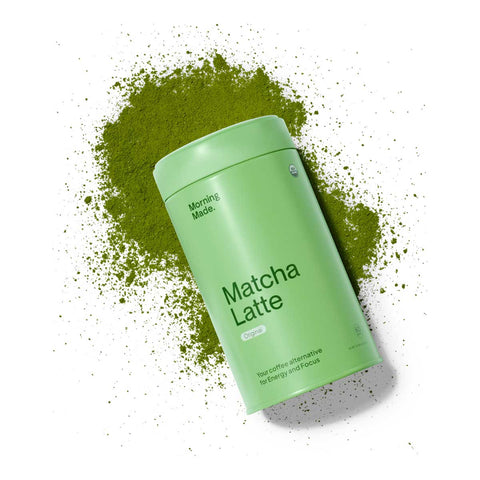 Morning Made Matcha Latte Sweetened Blend 300g lifestyle shot of the green tin lying in a spill of green matcha powder on a plain white background