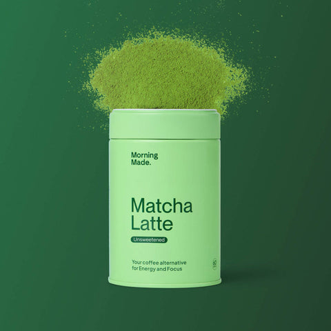 Morning Made Matcha Latte Unsweetened 60g lifestyle shot of the green tin with a cloud of matcha powder above it on a dark green backdrop
