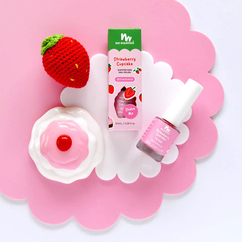 Nail polish styled on a pink and white cloud cut out with a crochet strawberry and toy cupcake.