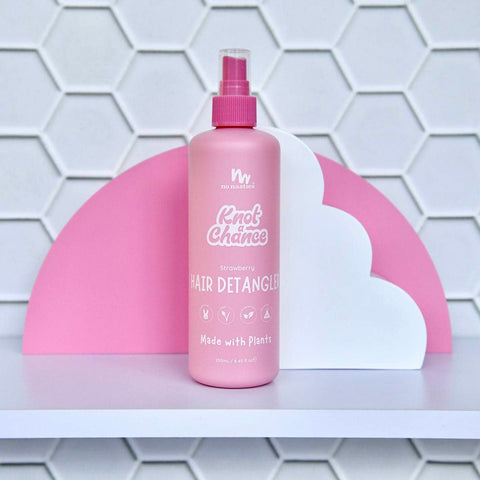 250ml spray bottle of No Nasties Slick Kids Hair Detangler Spray in Strawberry scent. Tiled white background with pink and white style elements.