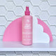 250ml spray bottle of No Nasties Slick Kids Hair Detangler Spray in Strawberry scent. Tiled white background with pink and white style elements.