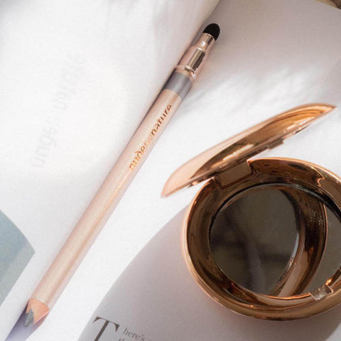 Eye pencil and compact mirror on a book.