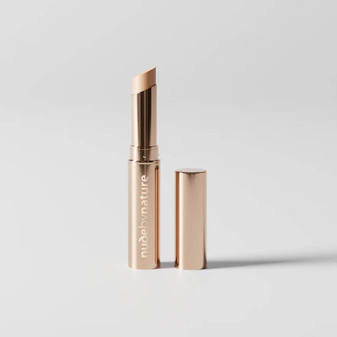 Stick concealer with Nude by Nature logo on a light grey background.