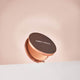 Compact powder case with 'nude by nature' branding on a soft pink background.