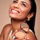 Woman holding a compact powder with a beige background.