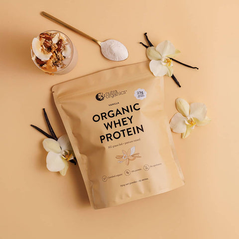 Nutra Organics Organic Whey Protein - Vanilla 750g package on a beige background with vanilla flowers and a spoon.