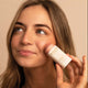 Model applying rose blush stick to her cheek. 