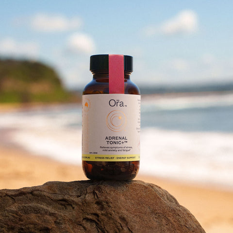 Jar of Ora Adrenal Tonic+ 60 capsules placed on a rock. Vegan supplement that relieves symptoms of stress, mild anxiety, and fatigue.