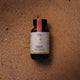 Jar of Ora Adrenal Tonic+ 60 capsules placed on sand. Vegan supplement that relieves symptoms of stress, mild anxiety, and fatigue.