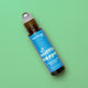 A roll-on bottle of Plant Therapy essential oil blend by sniffle stopper, featuring a bright blue label and amber glass bottle, set against a solid light green background.