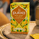 Pukka lemon, ginger, and manuka honey tea box on a woven surface