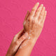 Hands with soap bubbles against a pink patterned background.