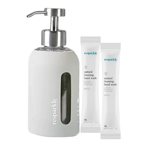 Grey soap dispenser with two tubes of resparkle natural foaming hand wash on a white background