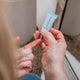 Person holding a small blue tube of Unuver eye gel with a blurred background.