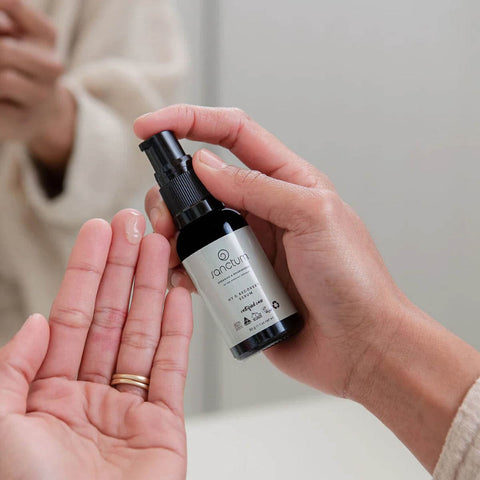 Person holding a bottle of 'arcturus' skincare product with another hand open palm up.